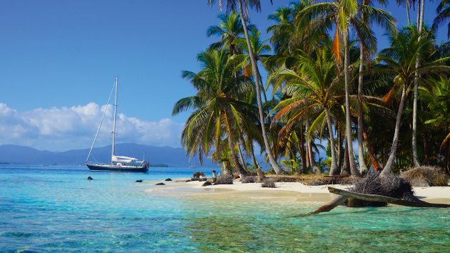A beautiful tropical landscape with a yacht and palm trees.